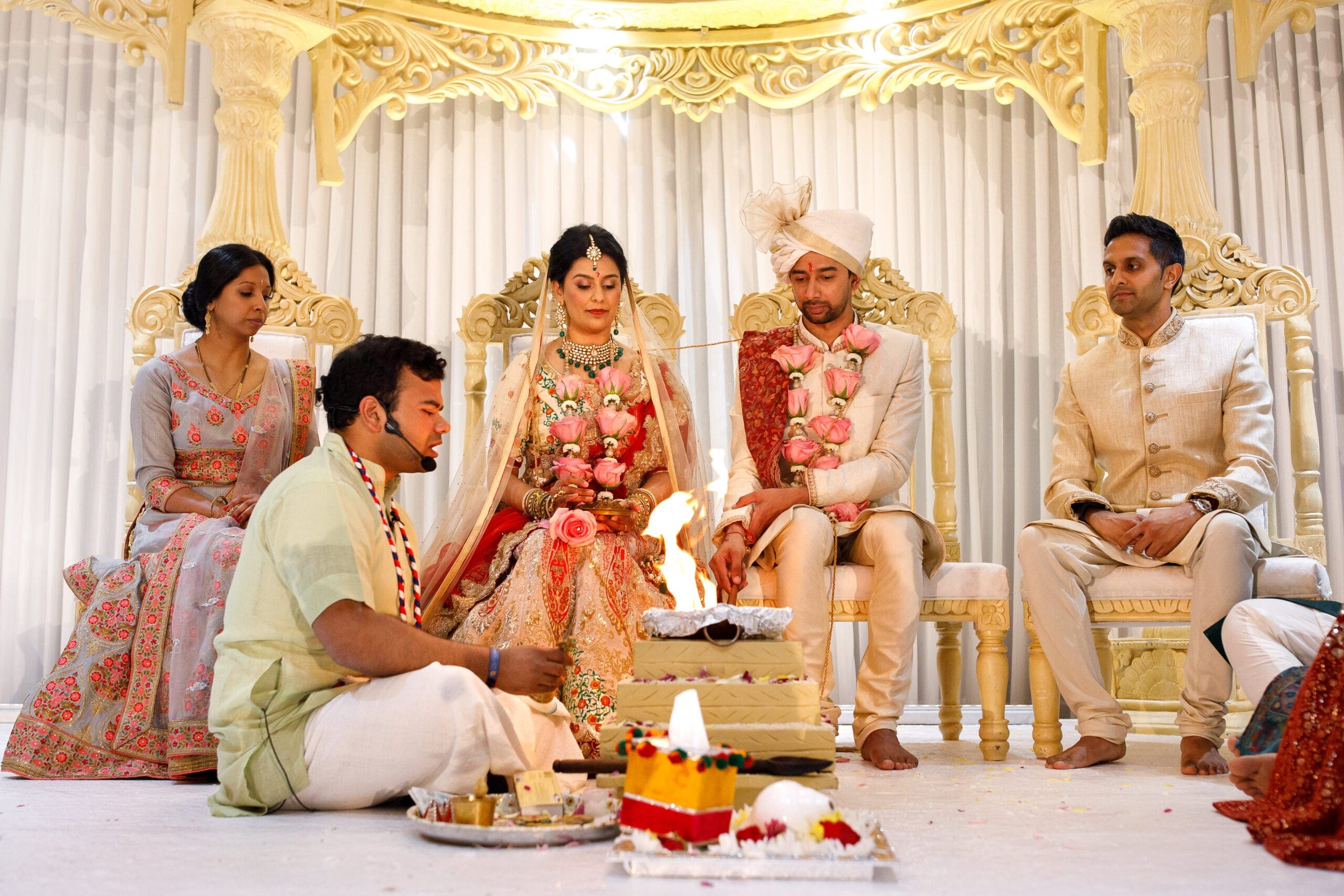 Couple sat down while a man lights a fire if their Hindu wedding