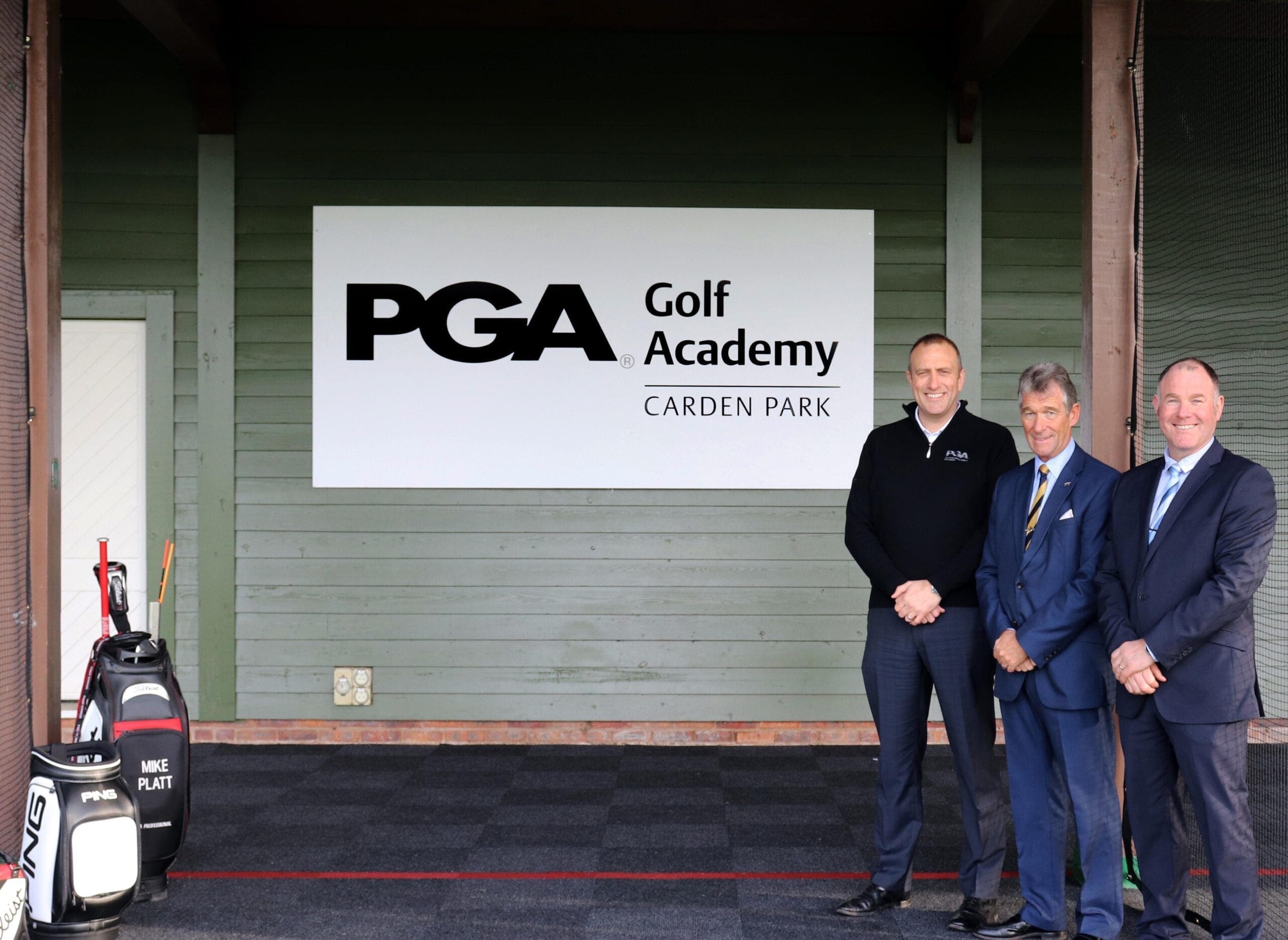 Three men stood inform of the PGA golf academy sign 