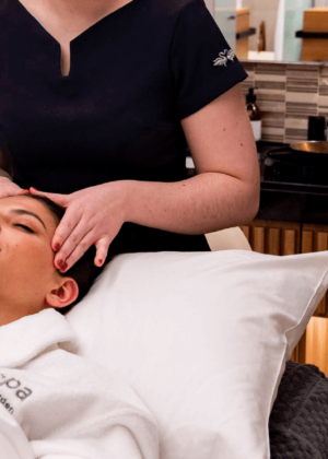 A woman getting her head massaged by a spa therapist